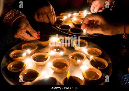 Riprese macro di diyas essendo illuminata da mano o candela per i religiosi indù festa di Diwali. Foto Stock