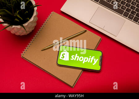 Tula, Russia - Agosto 19, 2019: Shopify logo su iphone X sulla tastiera portatile su bsckground rosso Foto Stock