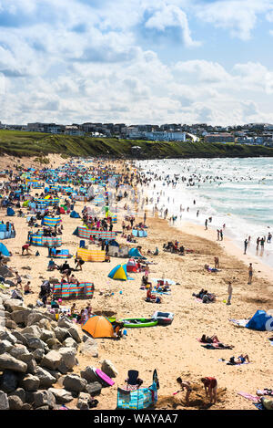 I turisti in vacanza in vacanza su una soleggiata spiaggia Fistral a Newquay in Cornovaglia. Foto Stock