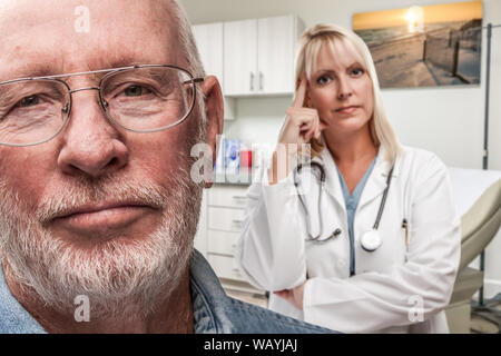 Di empatico medico in piedi dietro turbato Senior uomo adulto in ufficio. Foto Stock