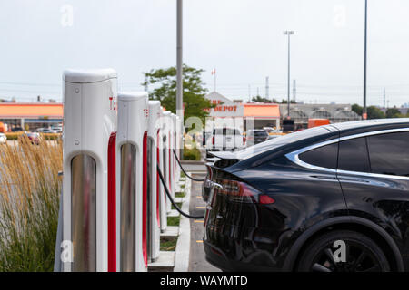 Black Tesla Model X inserito in Tesla Supercharger su un luminoso giorno d'estate. Foto Stock