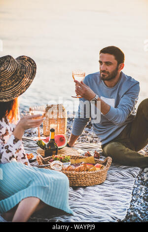 Coppia giovane avente un picnic con vino spumante e frutta Foto Stock