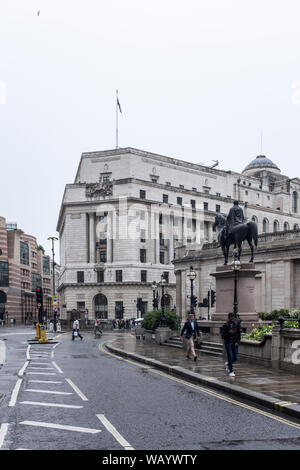 La gente camminare lungo Cornhill passato la statua del Duca di Wellington a cavallo in un giorno di pioggia nella città di Londra, Regno Unito Foto Stock