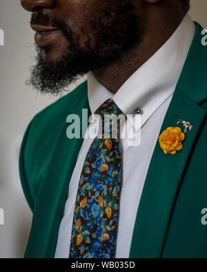 Primo piano verticale di una persona africana con la barba che indossa abito grigio con cravatta colorata Foto Stock