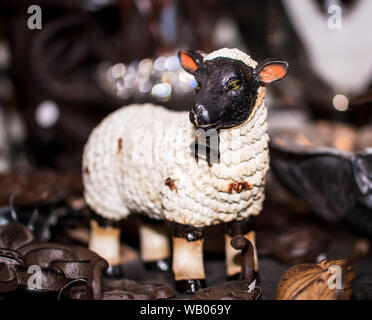 Ceramica pecore Vintage Figurine con faccia nera e il campanile a piedi tra oggetti di metallo. Il concetto di origine animale Foto Stock