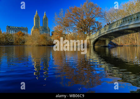 Archetto romantico Ponte sopra il lago di Central Park di New York in autunno con edifici di Manhattan in background e caduta foglie in primo piano Foto Stock