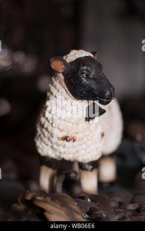 Ceramica pecore Vintage Figurine con faccia nera e il campanile a piedi tra oggetti di metallo. Il concetto di origine animale Foto Stock