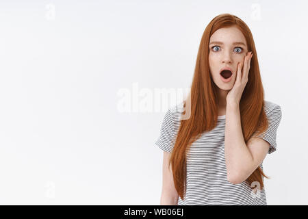 Scioccato stupito preoccupato senza parole redhead girl mascella caduta di allargare gli occhi di sympathizing toccare guancia imparare terribile cattive notizie reagire storditi, mostrare empatia Foto Stock