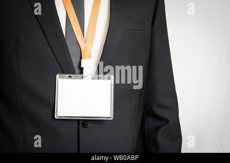 Imprenditore che mostra un vuoto bianco identità personale mockup con cordino arancione Foto Stock