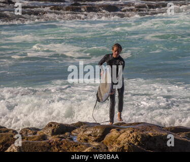 Mossel Bay, Sud Africa - Un misterioso giovane maschio surfer esce dall'acqua a La Punt un surf spot image in formato orizzontale Foto Stock