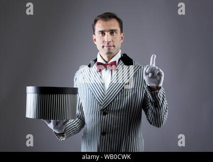 Il mago che mostra i trucchi con una scatola a strisce Foto Stock