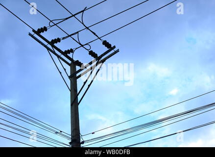 Le linee di alimentazione su un polo elettrico con cielo blu in background Foto Stock