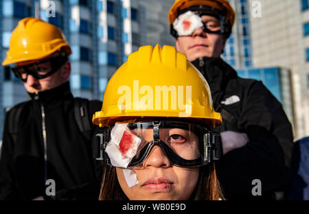 Berlino, Germania. 23 Ago, 2019. I dimostranti stand ad una veglia con giallo caschi, occhiali e simbolicamente coperto occhio destro di fronte all'ambasciata cinese e la richiesta di libertà per Hong Kong. Nella ex colonia della Corona britannica di Hong Kong vi sono state massicce manifestazioni di protesta contro il governo per più di due mesi. Le dimostrazioni sono state innescate da un disegno di legge del governo per l'estradizione di sospetti criminali in Cina. Credito: Paolo Zinken/dpa/Alamy Live News Foto Stock