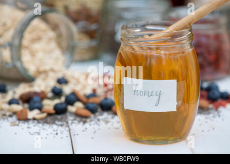 Un vasetto di miele con frutti di bosco, dadi e semi di Avena Foto Stock