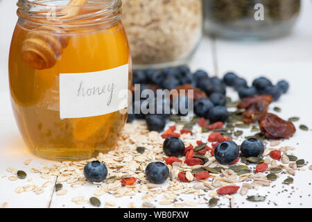 Un vasetto di miele con frutti di bosco, dadi e semi di Avena Foto Stock