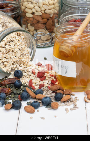 Un vasetto di miele con frutti di bosco, dadi e semi di Avena Foto Stock
