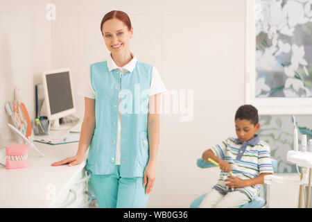 Bambino dentista sorridere mentre figlio visitando la sua al lavoro Foto Stock