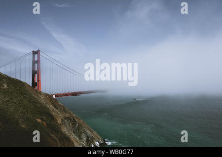 Foto del Golden Gate bridge in una nebbiosa giornata uggiosa con una barca nella baia Foto Stock