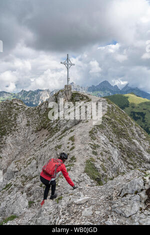 Bella e attiva donna anziana che si avvicina alla cima di Litnis Schrofen durante un'avventura in bicicletta ed escursione nella Valle di Tannheim, Tirol Austria Foto Stock