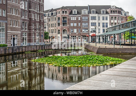 Helmond, Paesi Bassi, Agosto 16, 2019: la piazza centrale in Brandevoort quartiere postmoderno con un mercato in acciaio hall e case di mattoni reflec Foto Stock