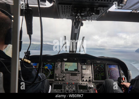 Elicottero cabina con i piloti che volano sopra le Isole Faroe. Danimarca Foto Stock