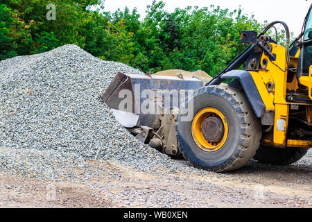 Giallo caricatore ruota bulldozer sta lavorando in cava contro lo sfondo di pietrisco di storage. Foto Stock