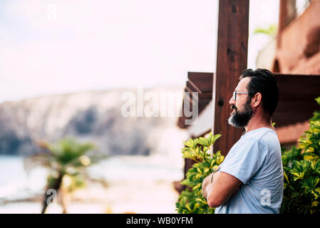 Barba caucasico adulto uomo in piedi guardando al di fuori di casa - il concetto di sicurezza e spazio esterno - persone con gli occhiali ritratto Foto Stock