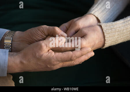 Il sambuco marito tenendo le mani della moglie di dare sostegno, close up Foto Stock