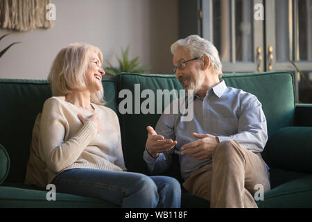 Felice senior vecchia coppia rilassante parlando di ridere seduta sul lettino Foto Stock