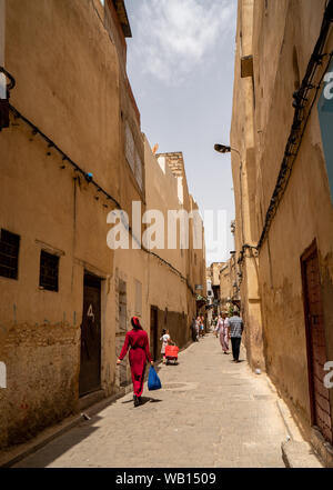 La popolazione locale in corso circa la loro attività nella strada stretta di Fez Foto Stock