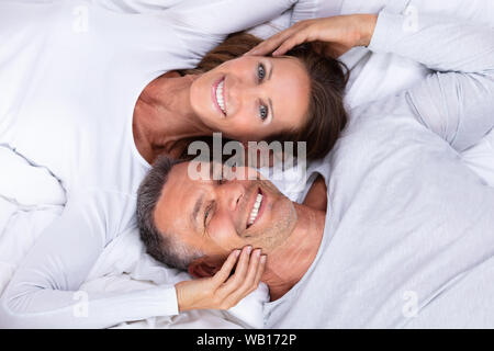 Angolo di Alta Vista di Felice Coppia Matura giacente sul letto Foto Stock