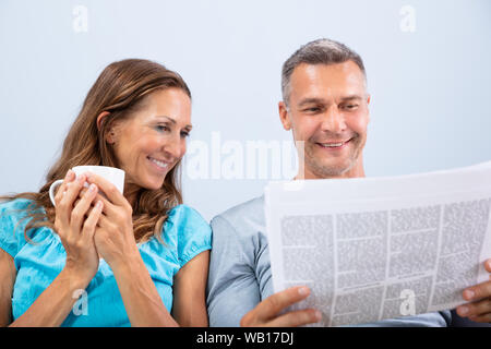 Ritratto di felice coppia matura la lettura quotidiano a casa Foto Stock