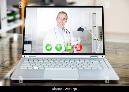 Medico sorridere mentre le videoconferenze su laptop in ospedale Foto Stock