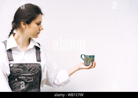 Donna con una ceramica blu mug in mano su uno sfondo di un muro bianco Foto Stock