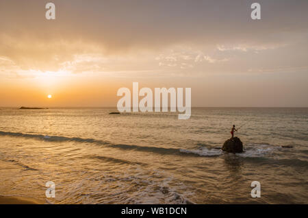 Il tramonto sotto il bel cielo azzurro sulla spiaggia Foto Stock