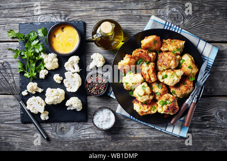 Tempura marocchino-style fritti cavolfiore servita su una piastra nera su un vecchio tavolo di legno con ingredienti su una scheda di ardesia, vista da sopra, cl Foto Stock