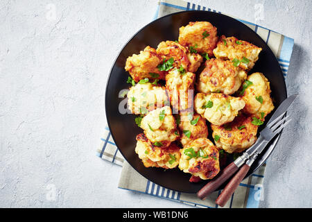 Tempura marocchino-style fritti cavolfiore servita su una piastra nera su una tavola di cemento, vista da sopra, close-up, flatlay, spazio vuoto Foto Stock