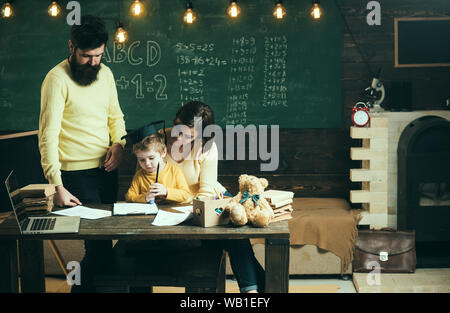 Concetto di homeschooling. La famiglia si preoccupa di educazione dei loro figlio. I genitori insegna figlio, lavagna su sfondo. Ragazzo ascolto di mamma e papà con att Foto Stock