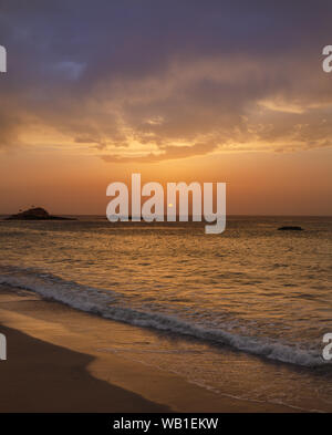 Il tramonto sotto il bel cielo azzurro sulla spiaggia Foto Stock