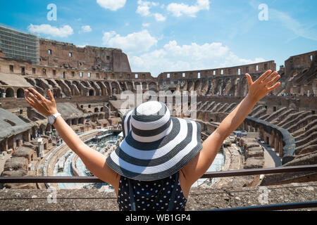 Vista posteriore di Felice turista femminile in piedi all'interno del Colosseo a Roma Guardando Arena Foto Stock