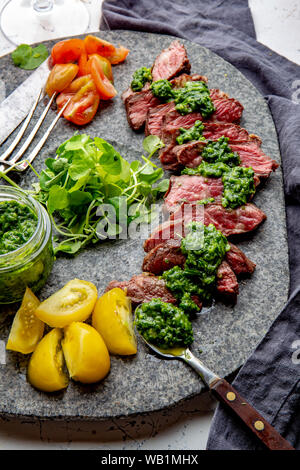 Fette di carne di manzo con salsa di chimmichuri grigio sulla lastra di pietra Foto Stock