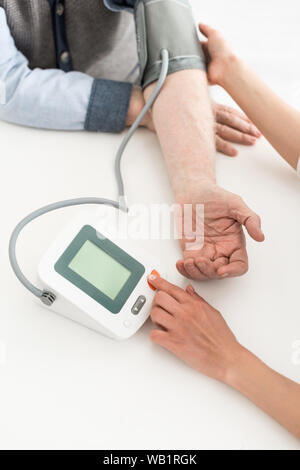 Vista ritagliata della donna premendo il pulsante sul sangue misuratore di pressione con spazio di copia sul display Foto Stock