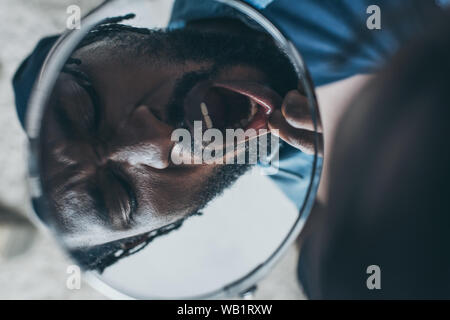 African American uomo guardando nello specchio mentre soffre di mal di denti Foto Stock