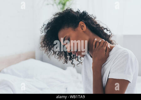 Infelice americano africano donna che soffrono di dolore al collo in camera da letto Foto Stock