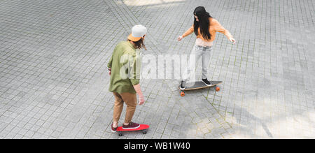 Angolo di alta vista della giovane donna con uomo a cavallo su skateboard su strada Foto Stock