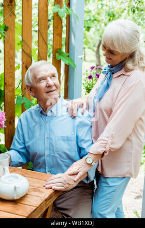 Allegro senior donna in piedi vicino al marito felice coppa di ritegno Foto Stock