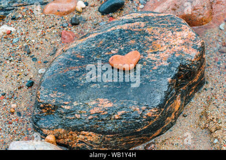 Pietra di mare rosso su nero, cuore di pietra Foto Stock