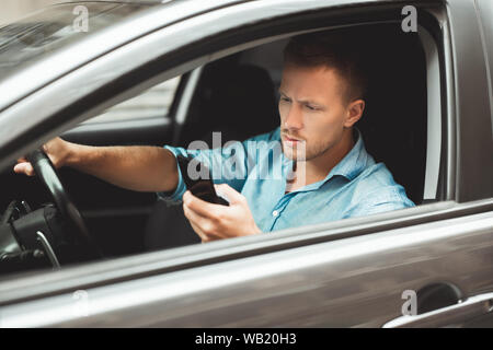 Giovane uomo bello rigidi unsafely controllando il suo smartphone durante la corsa Foto Stock