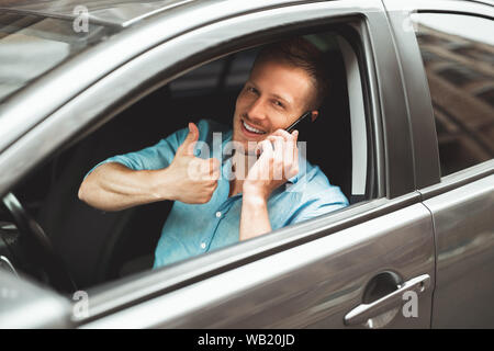 Giovane uomo bello rigidi aventi unsafely conversazione sul suo smartphone sulla corsa che mostra come la sign Foto Stock