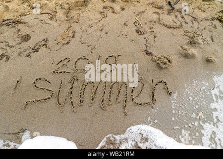 Spiaggia di sabbia con un'onda corre sulla parola estate 2019 Foto Stock